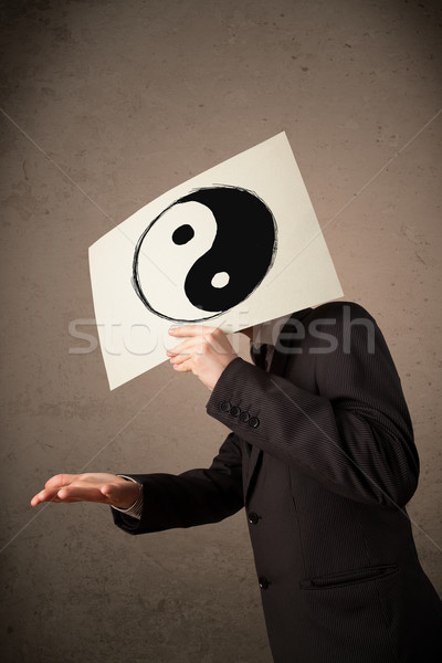 Businessman holding a paper with a yin-yang on it in front of hi Stock photo © ra2studio
