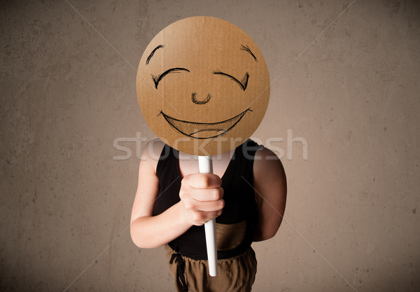 Stock photo: Young woman holding a smiley face board