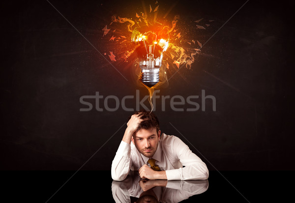 Businessman sitting under a blowing idea bulb Stock photo © ra2studio