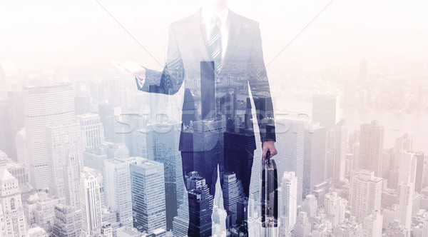 Business man standing on roof with city in the background Stock photo © ra2studio