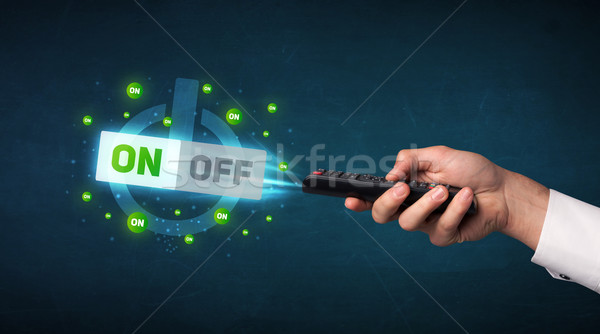 Hand with remote control and on-off signals Stock photo © ra2studio