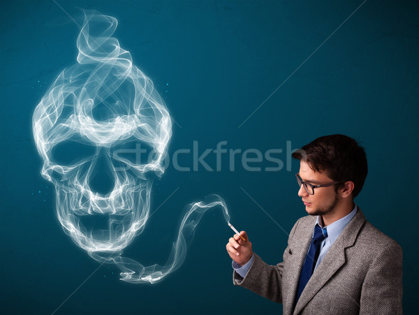 Young man smoking dangerous cigarette with toxic skull smoke Stock photo © ra2studio