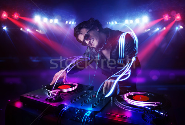 Disc jockey playing music with light beam effects on stage Stock photo © ra2studio