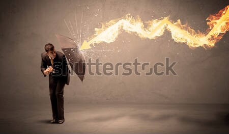 Business man defending himself from a fire arrow with an umbrell Stock photo © ra2studio