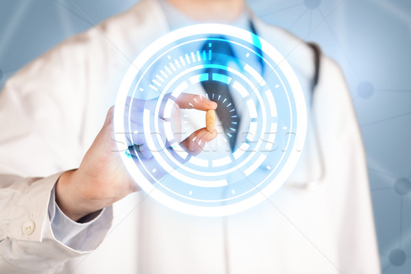 Male doctor holding a pill with glowing circles Stock photo © ra2studio