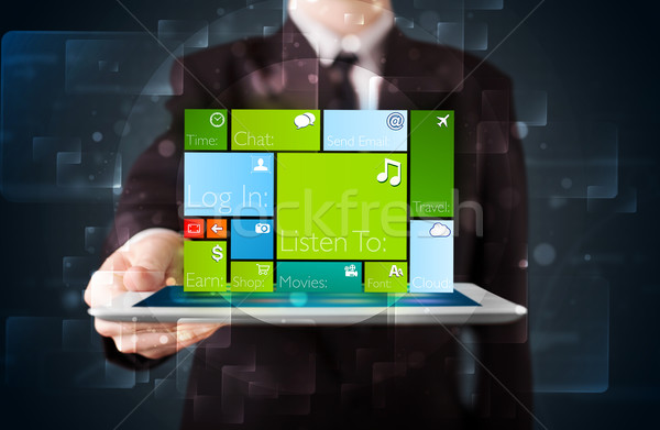 Stock photo: Young businessman holding a tablet with modern software operational system