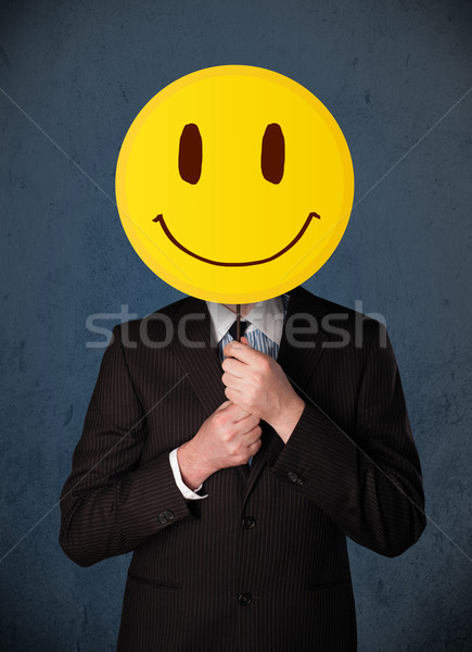 Businessman holding a smiley face emoticon Stock photo © ra2studio