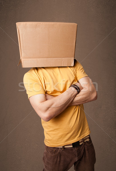 Stock photo: Young man gesturing with a cardboard box on his head