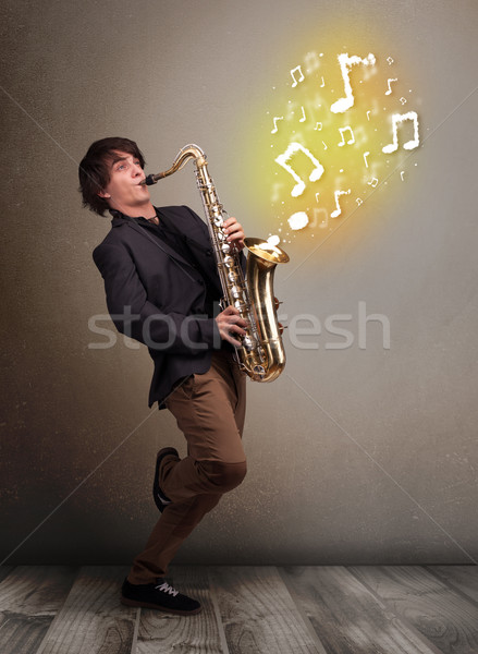 Handsome musician playing on saxophone with musical notes Stock photo © ra2studio