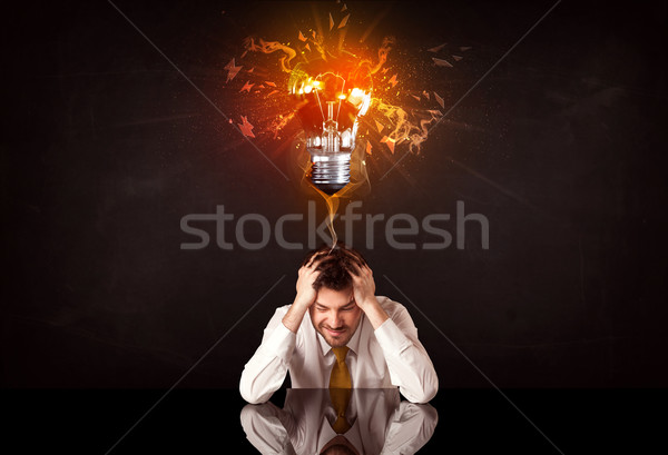 Businessman sitting under a blowing idea bulb Stock photo © ra2studio