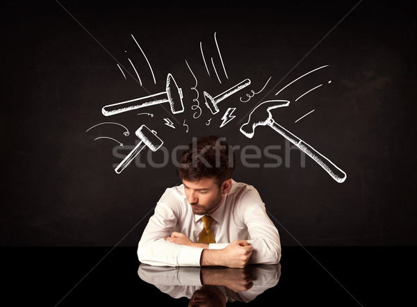 Depressed businessman sitting under hammer marks Stock photo © ra2studio
