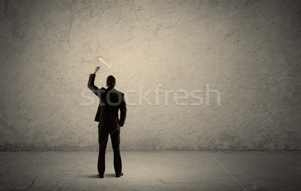 Salesman with roller standing at empty wall Stock photo © ra2studio