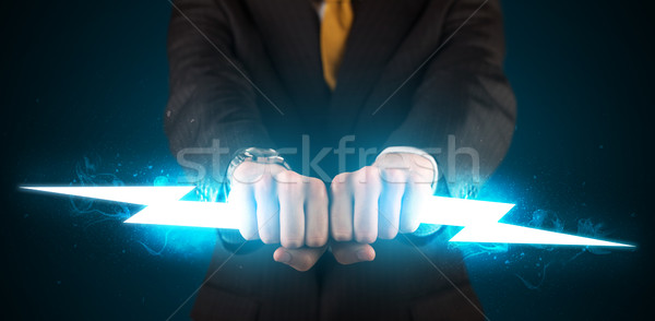 Business man holding glowing lightning bolt in his hands Stock photo © ra2studio