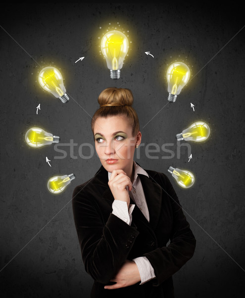 Stock photo: Young woman thinking with lightbulb circulation around her head