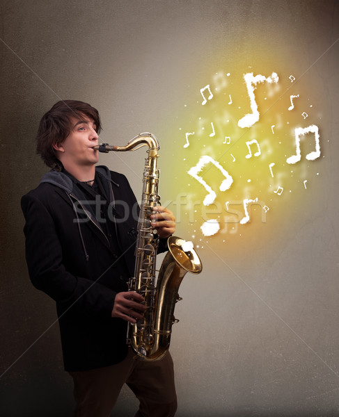 Guapo músico jugando saxófono notas musicales jóvenes Foto stock © ra2studio