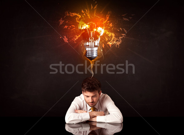 Businessman sitting under a blowing idea bulb Stock photo © ra2studio