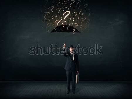 Stock photo: Businessman with umbrella and a lot of drawn question marks