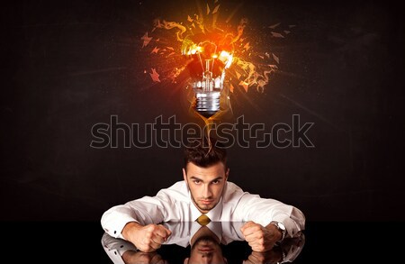 Businessman sitting under a blowing idea bulb Stock photo © ra2studio