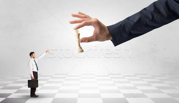 Stock photo: Businessman fighting against big chessman on a big hand