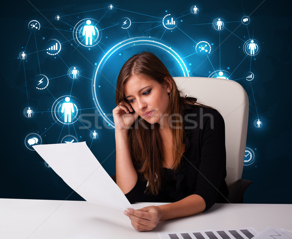 Businesswoman sitting at desk with social network icons Stock photo © ra2studio