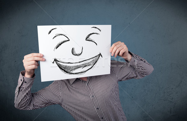 Stock photo: Businessman holding a paper with smiley face in front of his hea