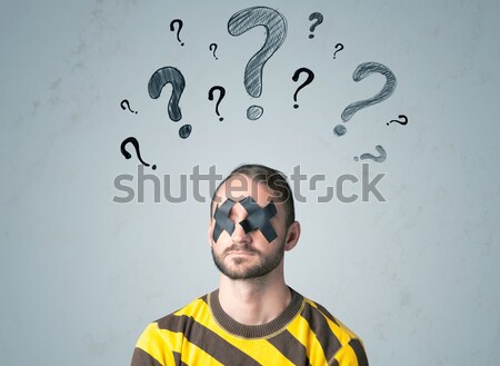 Young man with glued eye and question mark symbols Stock photo © ra2studio