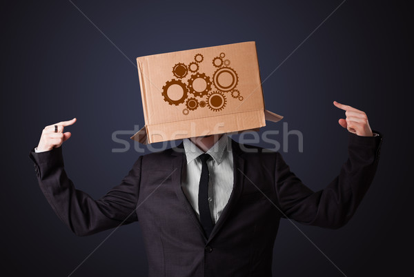 Young man gesturing with a cardboard box on his head with spur w Stock photo © ra2studio