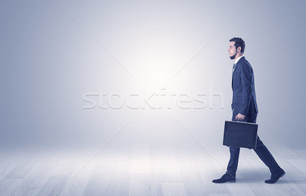 Businessman walking in front of an empty wall Stock photo © ra2studio