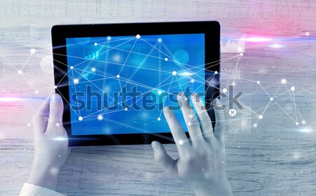 Stock photo: Hand holding tablet with linked graphs and charts concept