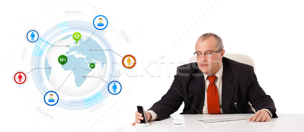 businessman sitting at desk and holding a mobilephone with globe and social icons, isolated on white Stock photo © ra2studio