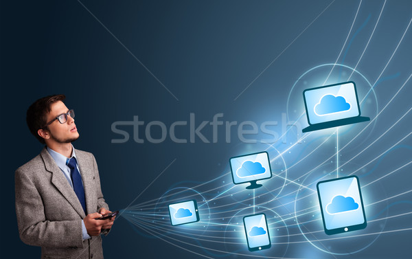 Stock photo: Handsome man typing on smartphone with cloud computing