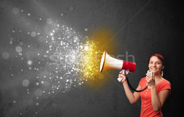 Woman shouting into megaphone and glowing energy particles explode concept Stock photo © ra2studio
