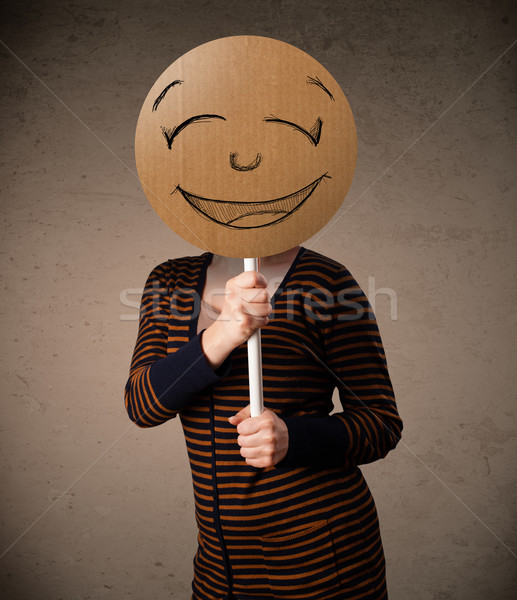 Stock photo: Young woman holding a smiley face board