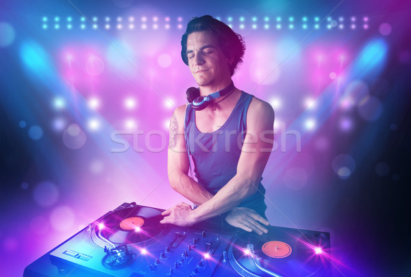Disc jockey mixing music on turntables on stage with lights and  Stock photo © ra2studio