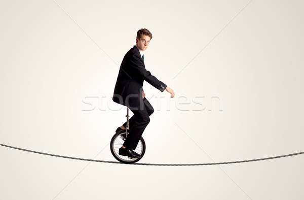 Extreme business man riding unicycle on a rope Stock photo © ra2studio