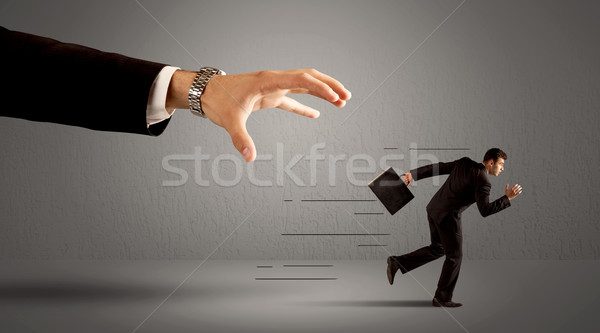 Stock photo: Businessman running away from a huge hand