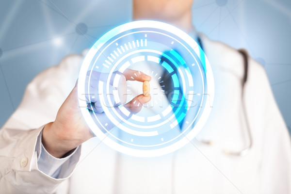 Male doctor holding a pill with glowing circles Stock photo © ra2studio