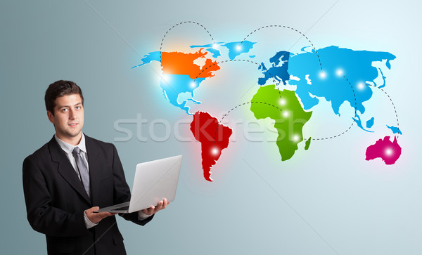 young man holding a laptop and presenting colorful world map Stock photo © ra2studio