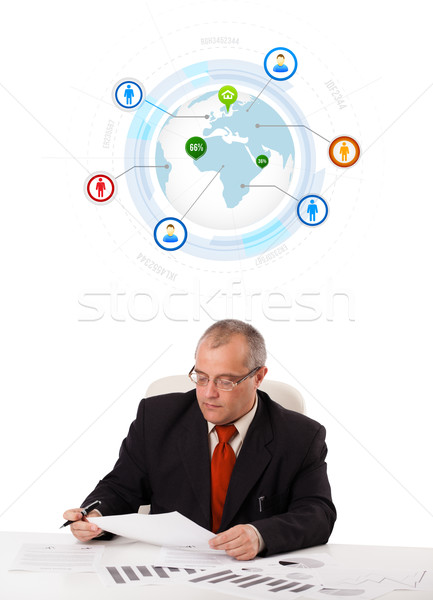 businessman sitting at desk with a globe and social icons Stock photo © ra2studio