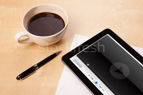 Workplace with tablet pc showing media player and a cup of coffee on a wooden work table closeup Stock photo © ra2studio