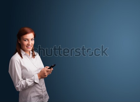 Young woman standing and typing on her phone with copy space Stock photo © ra2studio