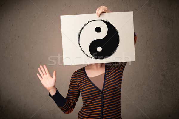 Woman holding a paper with a yin-yang on it in front of her head Stock photo © ra2studio