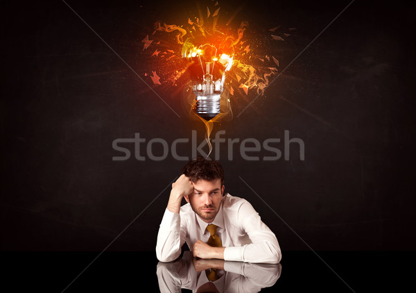 Businessman sitting under a blowing idea bulb Stock photo © ra2studio