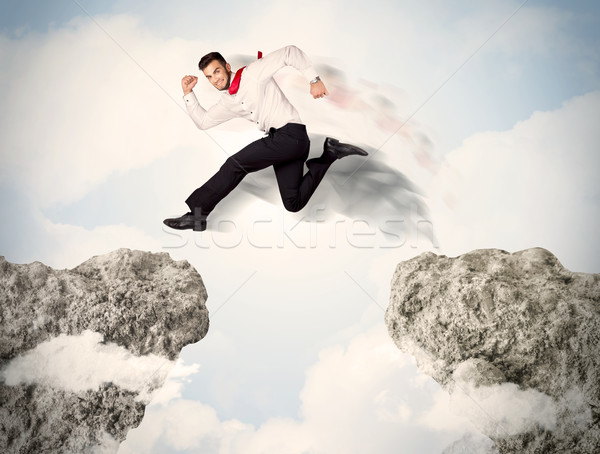 Happy business man jumping over a cliff  Stock photo © ra2studio