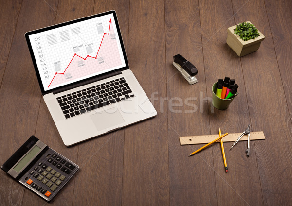 Computer desk with laptop and red arrow chart in screen Stock photo © ra2studio