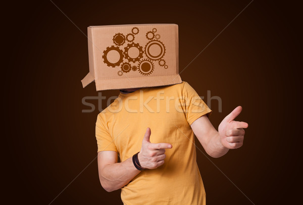 Young man gesturing with a cardboard box on his head with spur w Stock photo © ra2studio