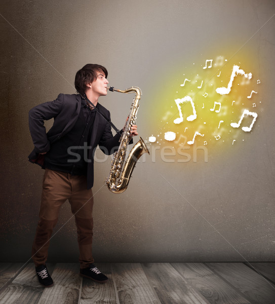 Handsome musician playing on saxophone with musical notes Stock photo © ra2studio