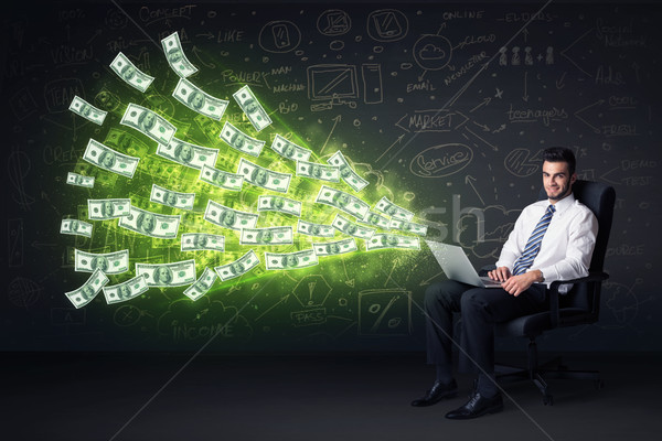 Businessman sitting in chair holding laptop with dollar bills co Stock photo © ra2studio