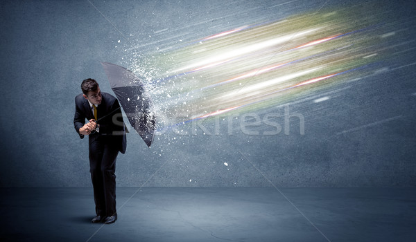 Business man defending light beams with umbrella concept Stock photo © ra2studio