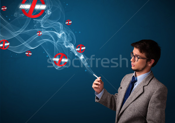 Attractive young man smoking dangerous cigarette with no smoking signs Stock photo © ra2studio